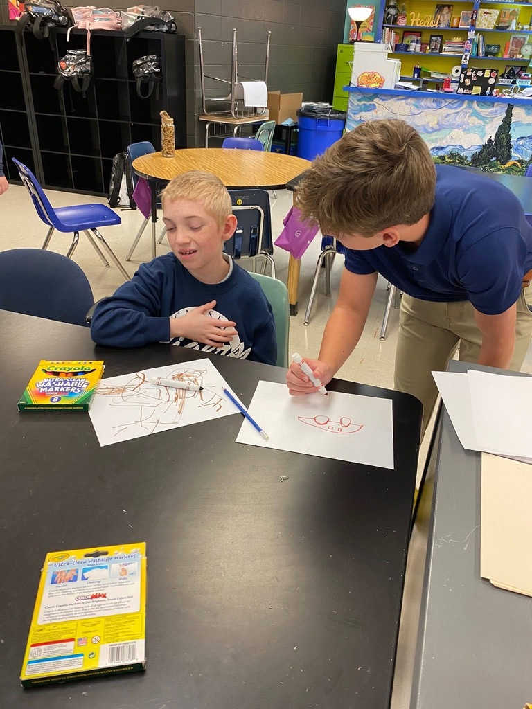 Students working in art classroom, peer helping