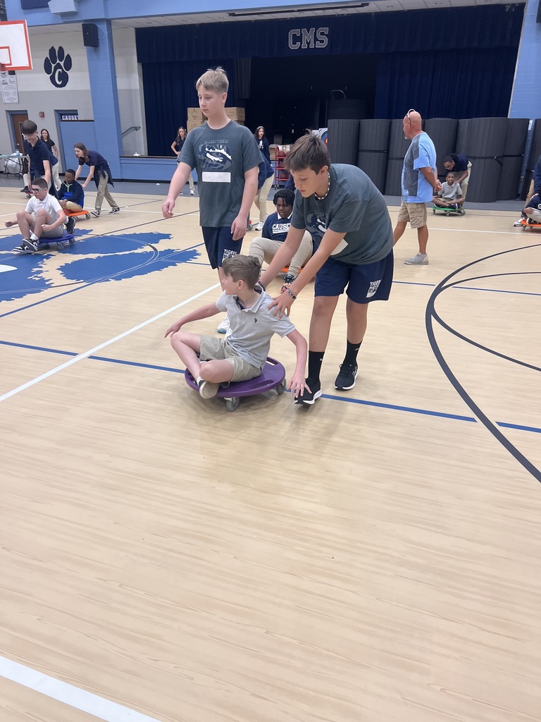 Students helping others in gym with scooters