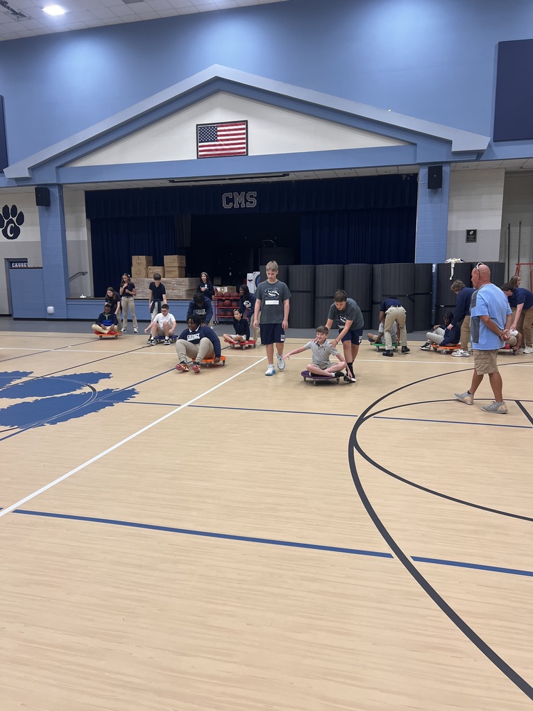 Group of students in a gym helping others on scooters