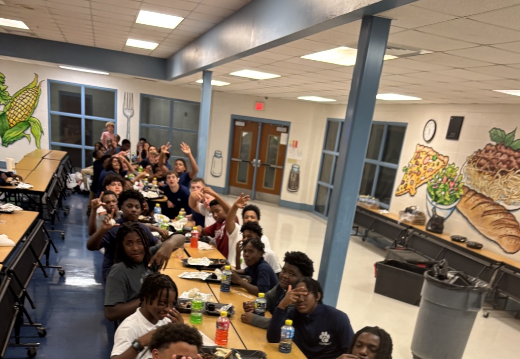Group of boys sitting around a cafeteria table, eating food
