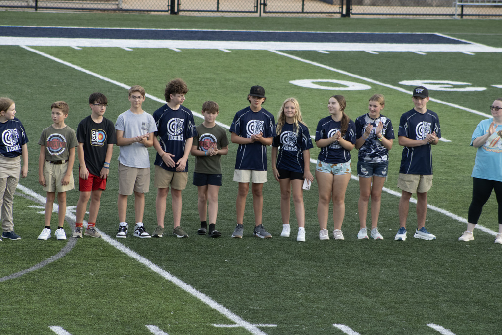 Group of kids on a football field, standing in a line