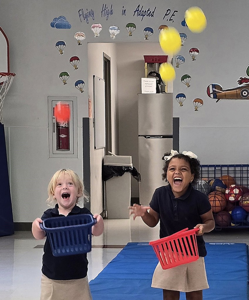 Two little girls with big smiles try to catch balls with baskets