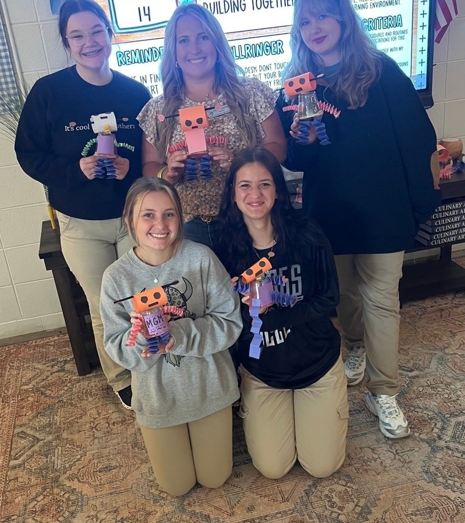 Six students holding robots made of construction paper