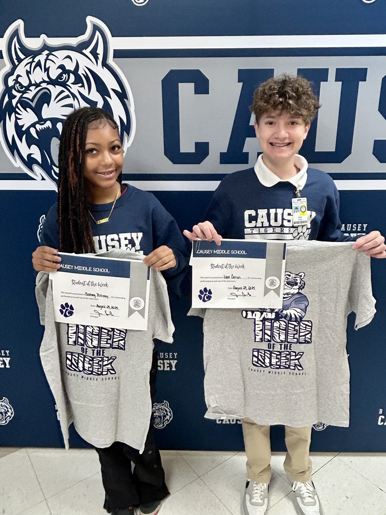 Boy and girl standing in front of a backdrop holding a certificate and t-shirt