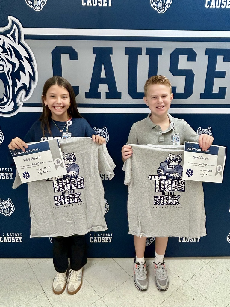 Boy and girl standing in front of a backdrop holding a certificate and t-shirt