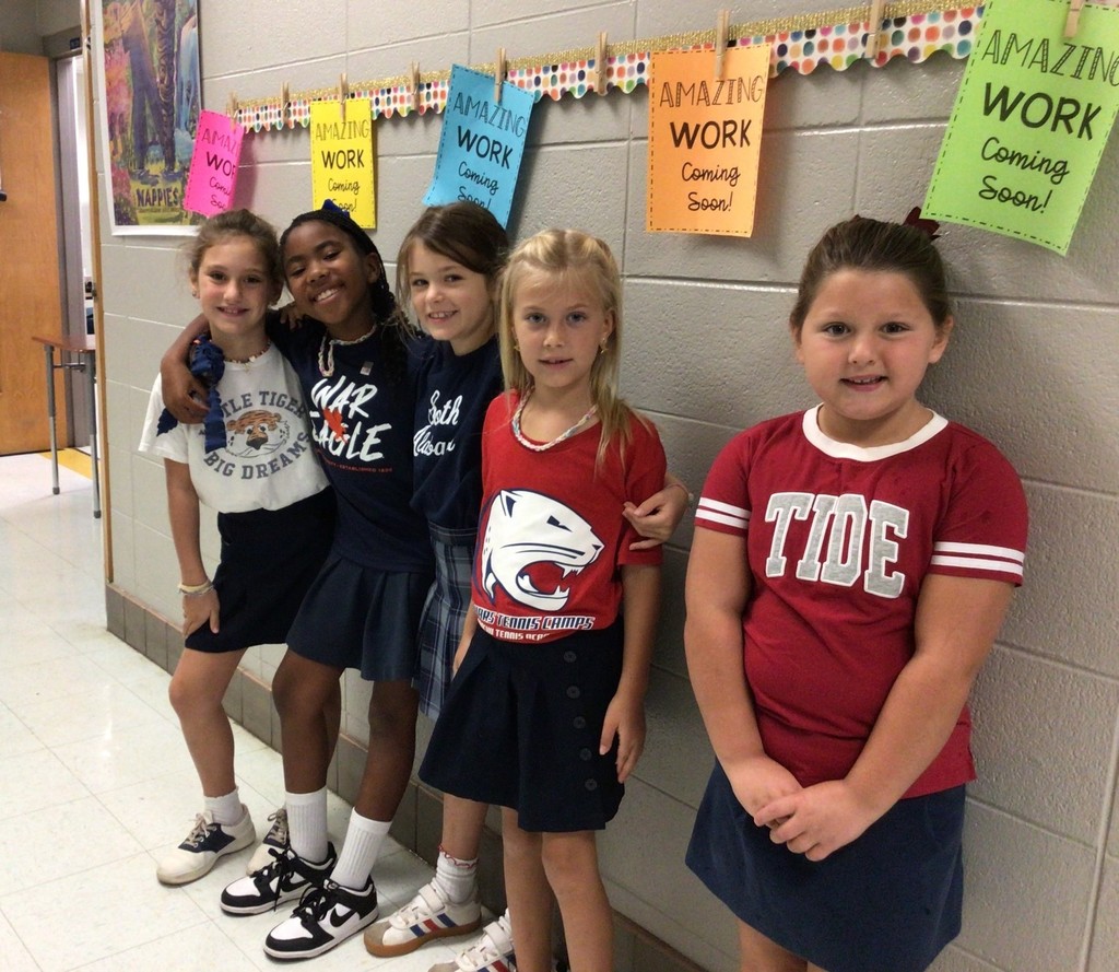 A group of girls wearing shirts from their favorite college football teams