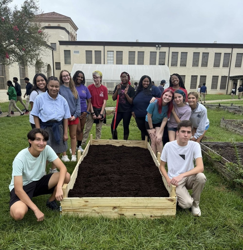 Students posing by a raised garden bed