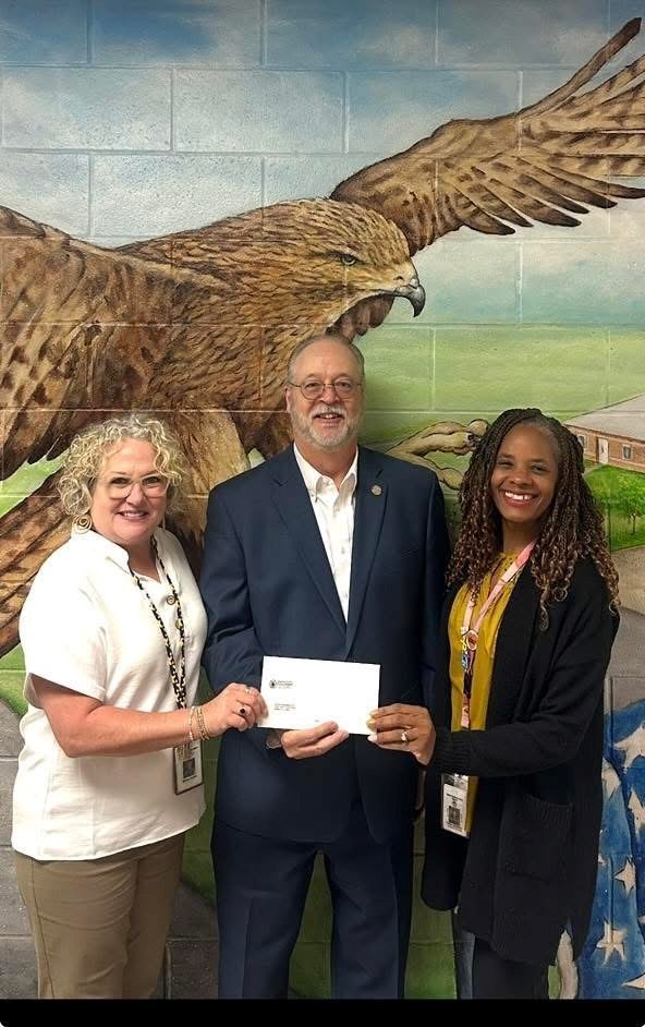 Mrs. Griffin, principal of Dawes Intermediate School, Dr. Shirey and Talia Johnson, Assistant Principal of Dawes Intermediate School displaying the check Dr. Shirey presented.
