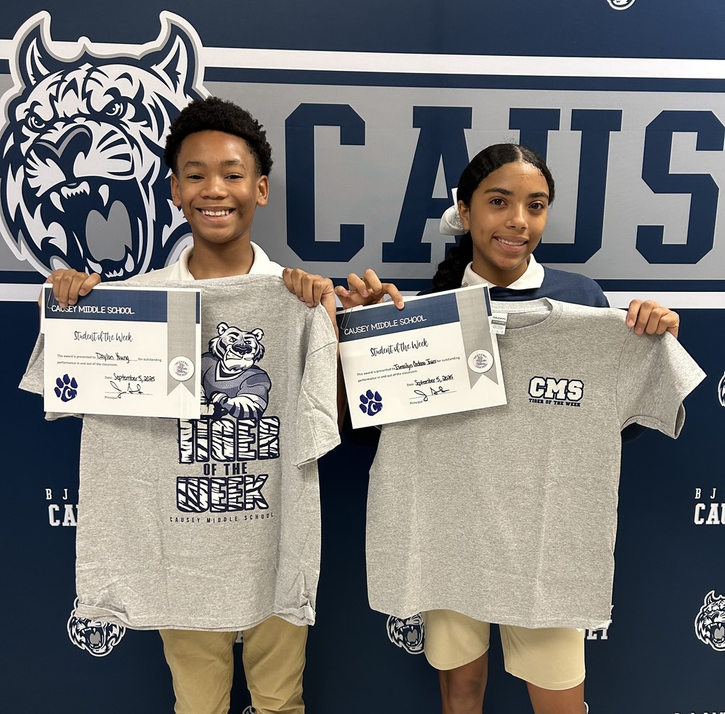 A boy and girl standing in front of a backdrop holding a t-shirt and certificate