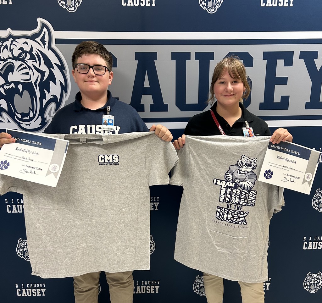 A boy and girl standing in front of a backdrop holding a t-shirt and certificate