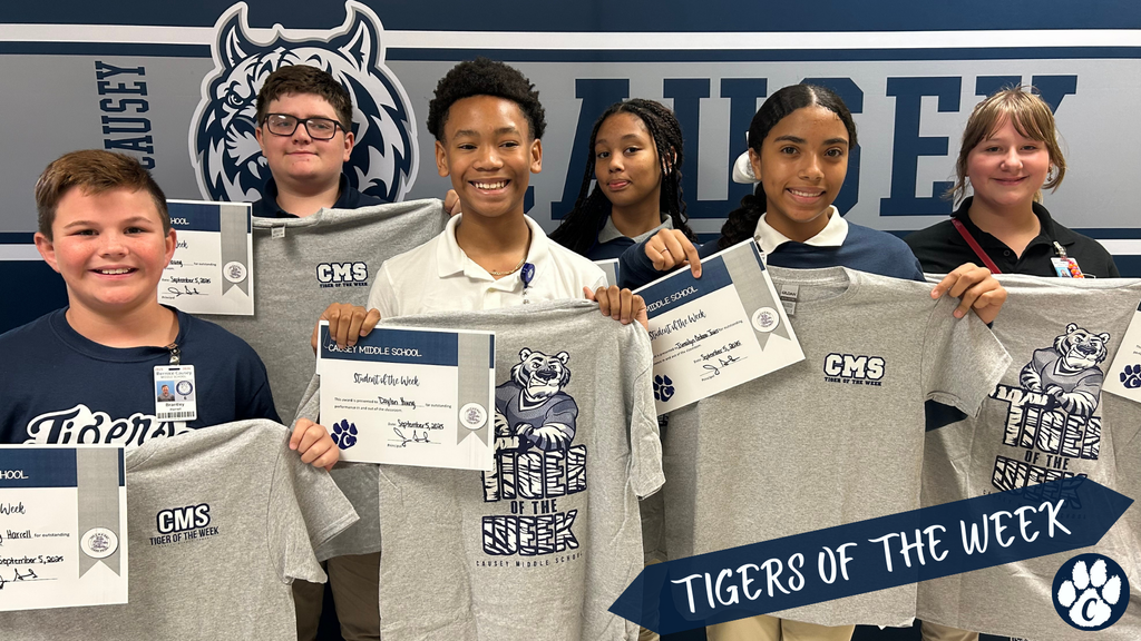 A group of students holding up t-shirts and certificates