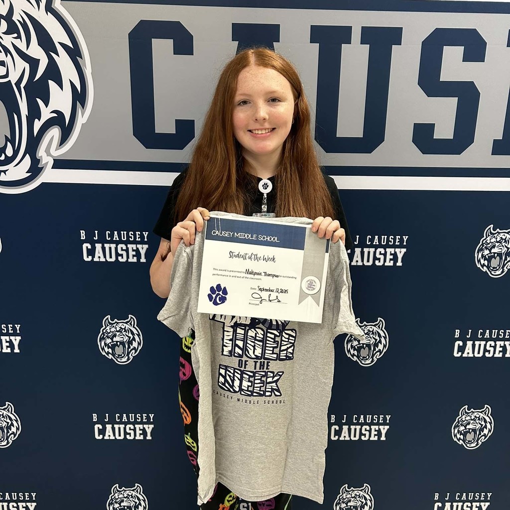 A girl holding up a t-shirt and certificate