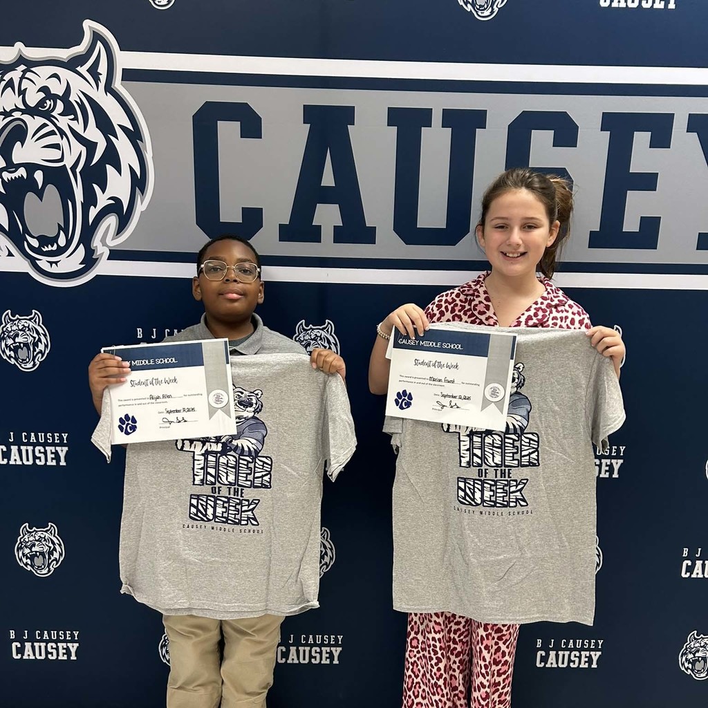 2 students holding a t-shirt and certificate