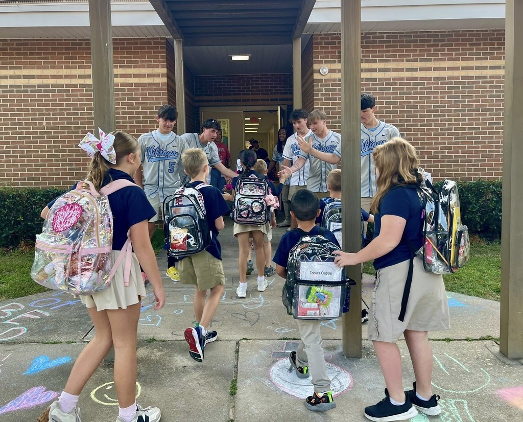 High school baseball players high-fiving elementary students outside a school