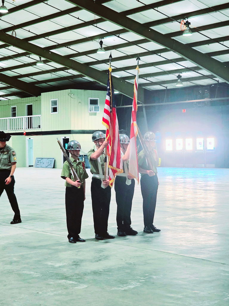 Group of four students in uniform performing color guard with flags