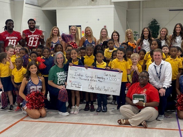 Indian Springs students and educators post with South Alabama cheerleaders and football players with a large check