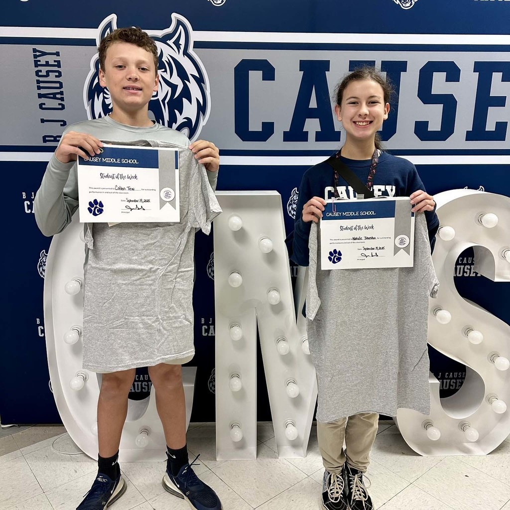 2 students holding up t-shirts and certificates