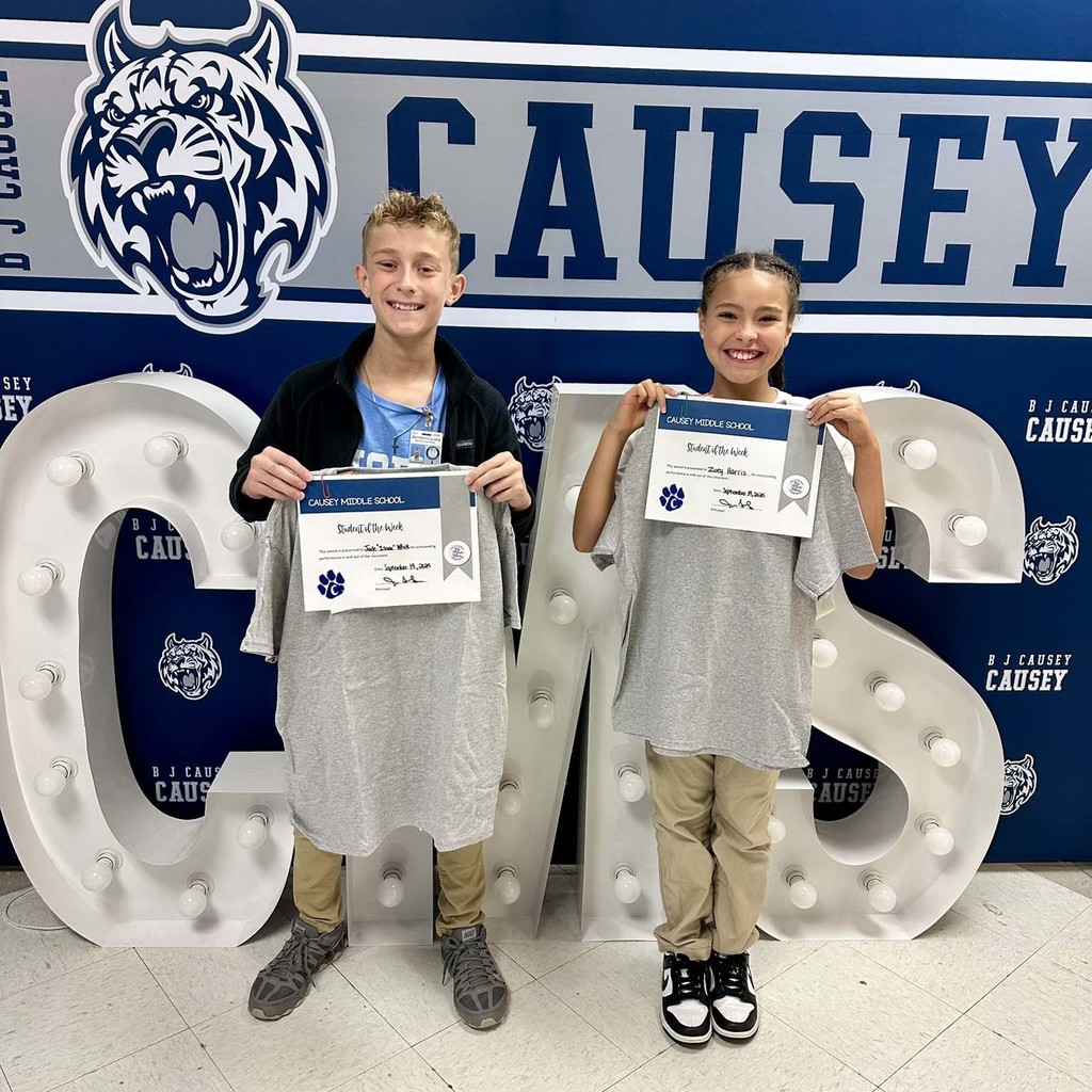 2 students holding up t-shirts and certificates