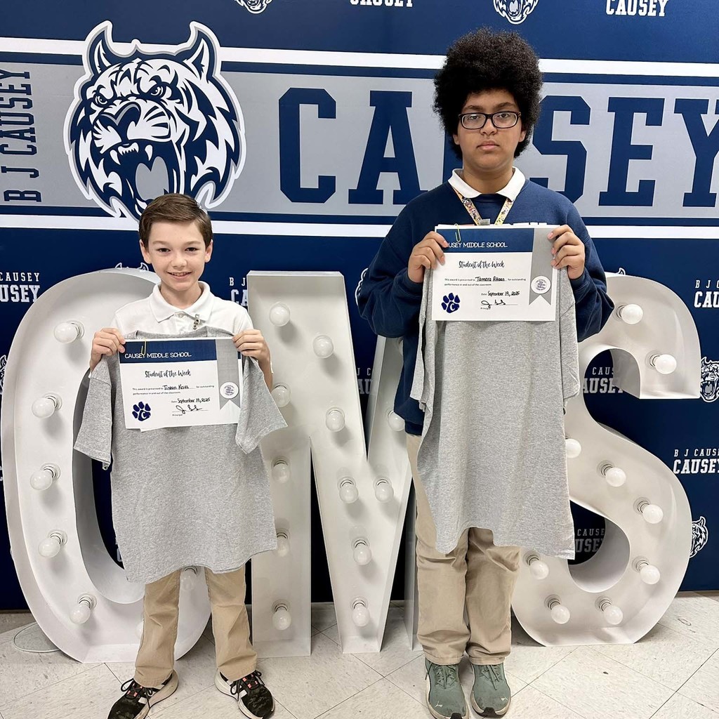 2 students holding up t-shirts and certificates
