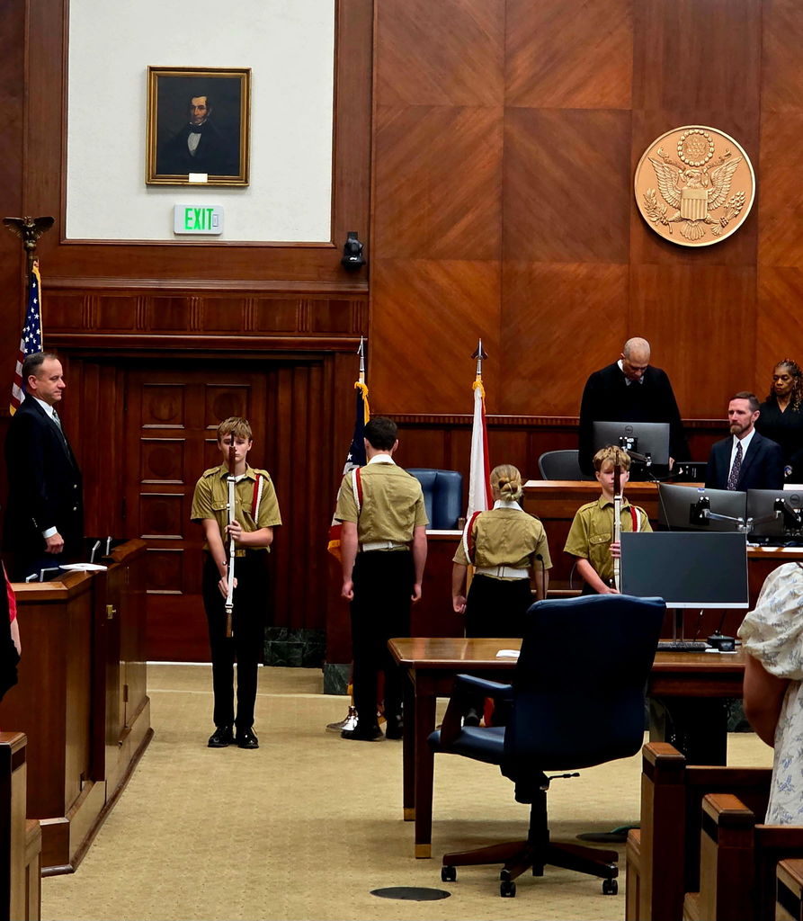 Courtroom with young cadets presenting arms, everyone standing