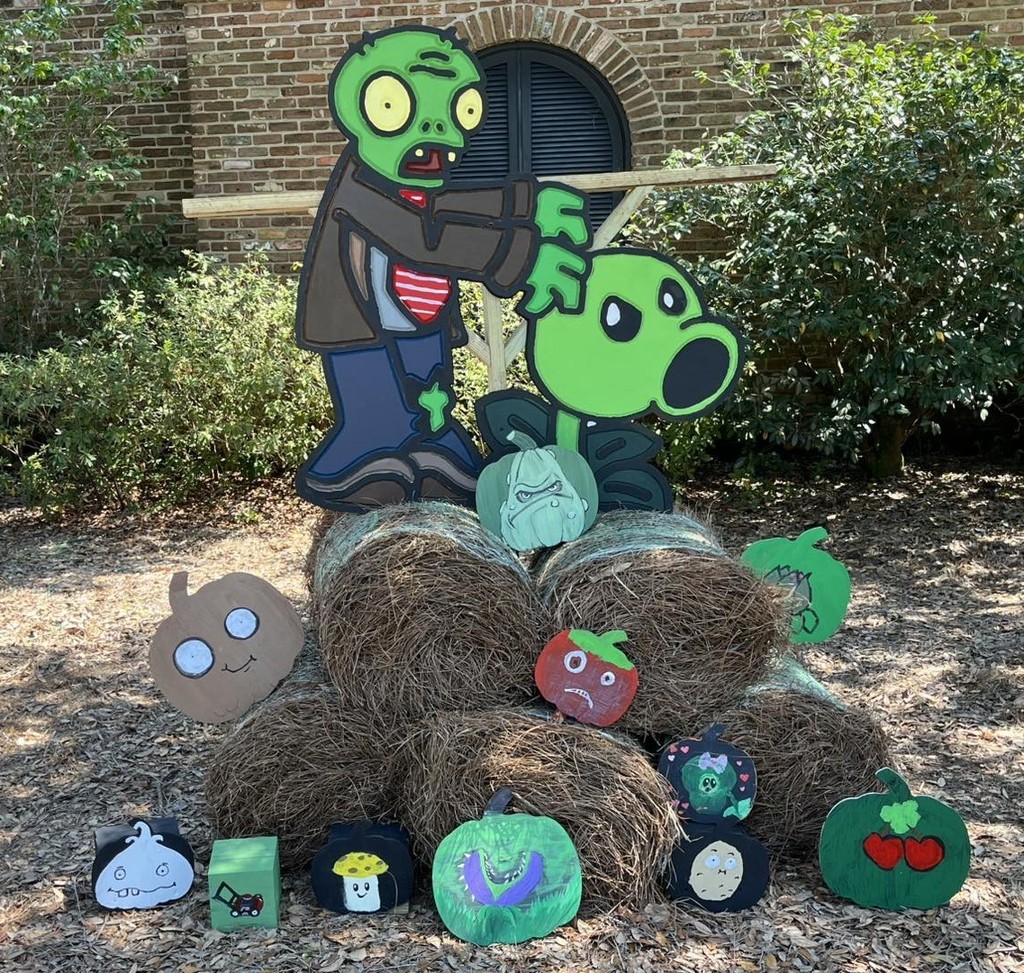 A Halloween decoration featuring pumpkins and a zombie atop bales of hay
