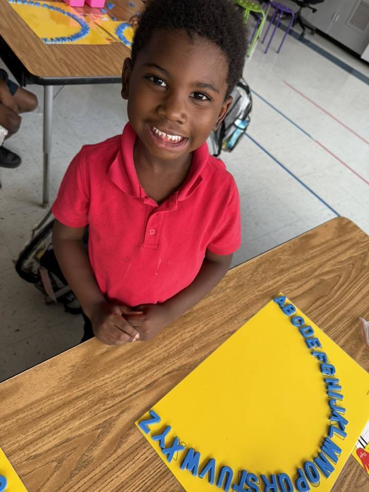 A student at a desk, with an alphabet arc in front of him