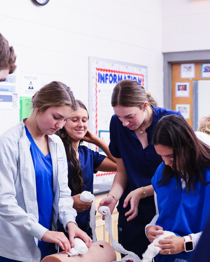 Four students practicing applying gauze to stop bleeding