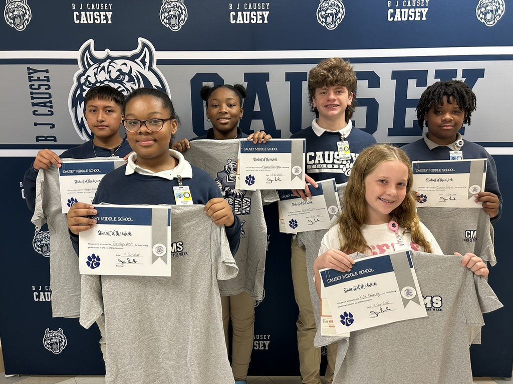 A group of students holding up t-shirts and certificates