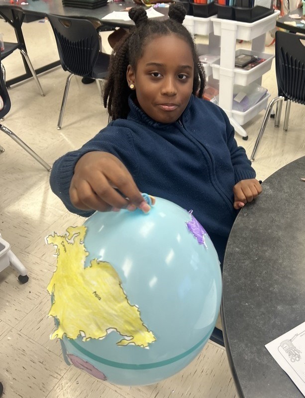 A student holding a balloon globe