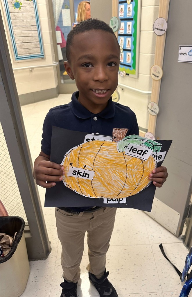 A student holding a drawing that shows the parts of a pumpkin