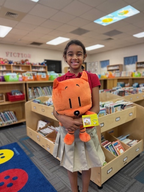 Amiyah with Cat Kid plush in the library