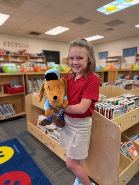 Arianna with Dog Man plush in the library