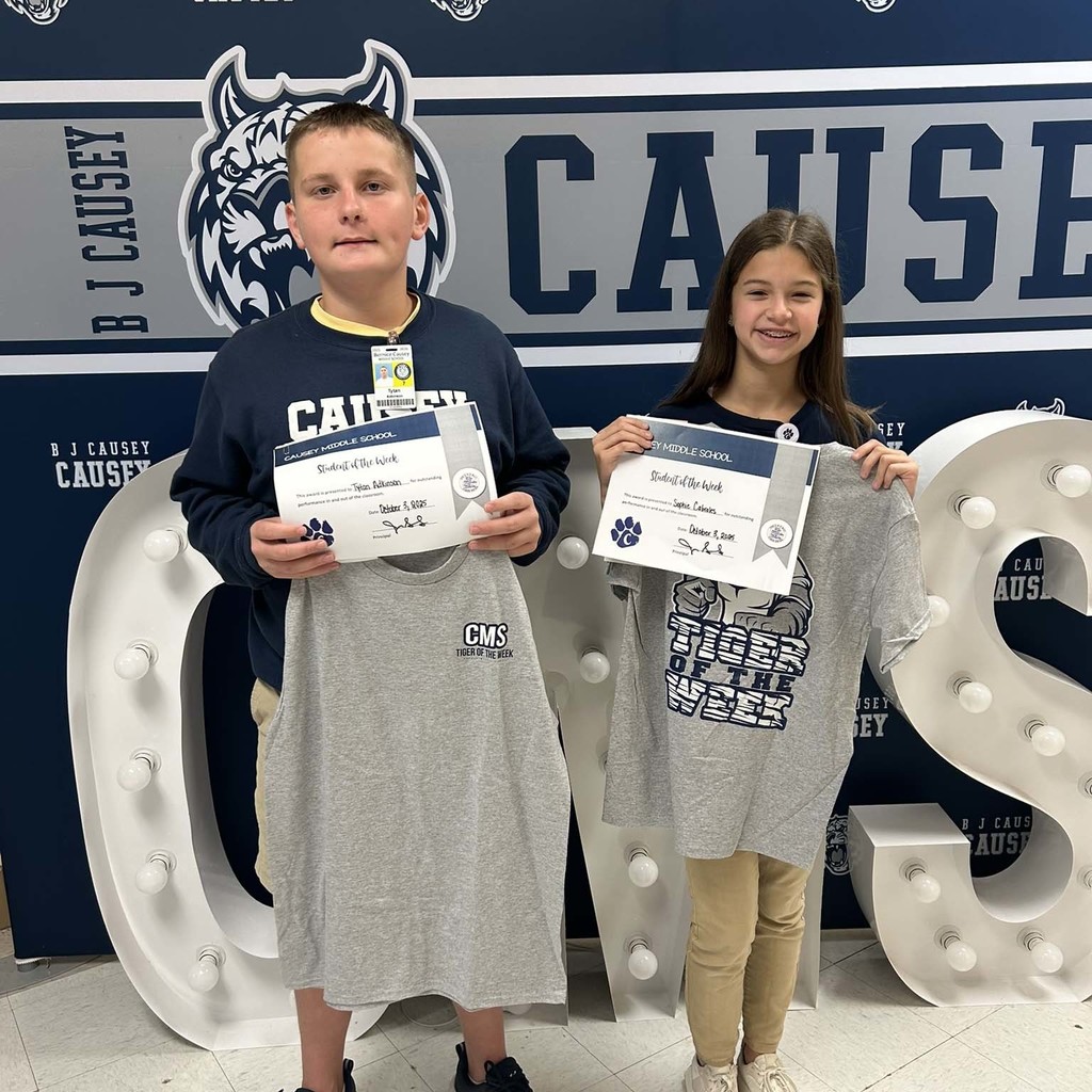 2 students holding up t-shirts and certificates