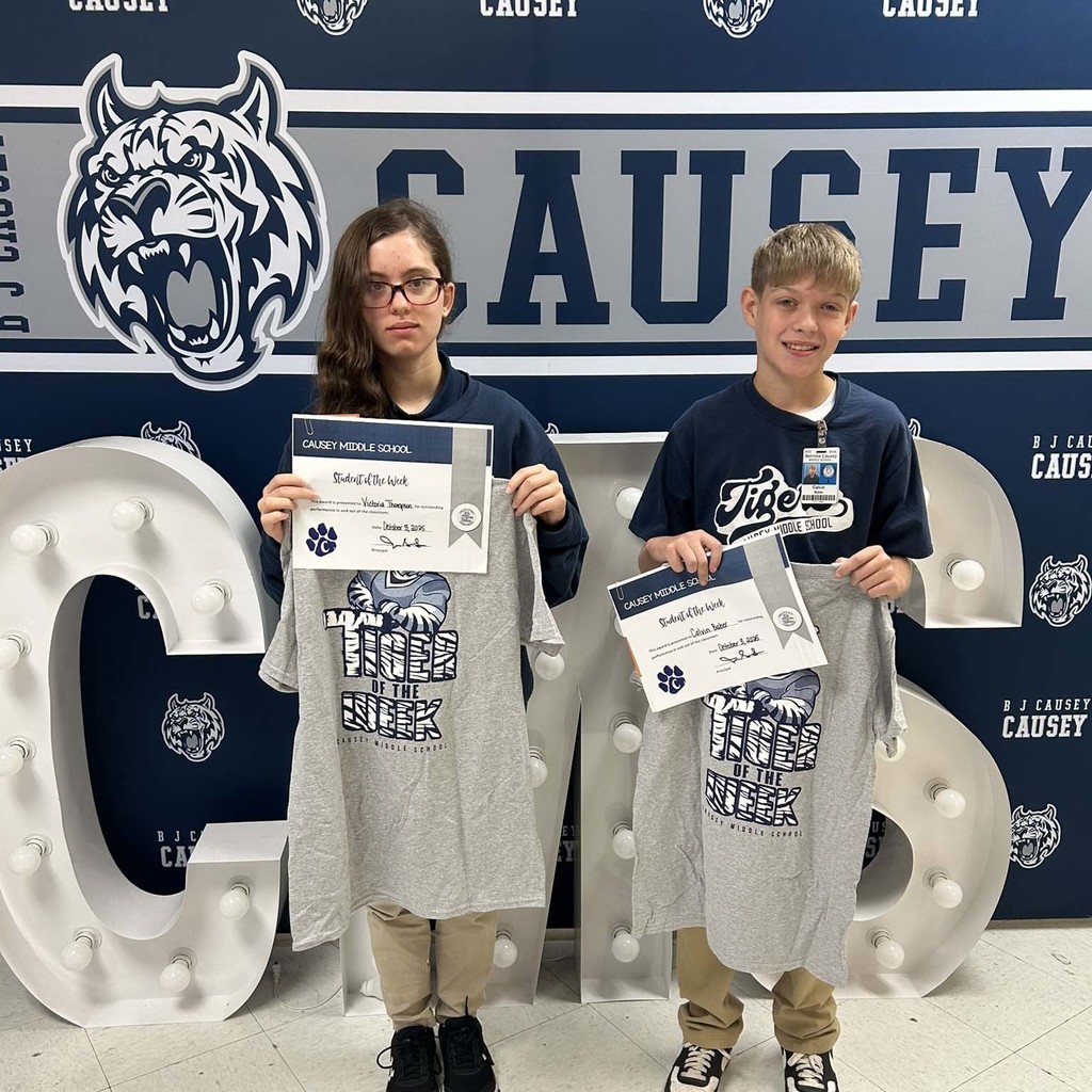 2 students holding up t-shirts and certificates