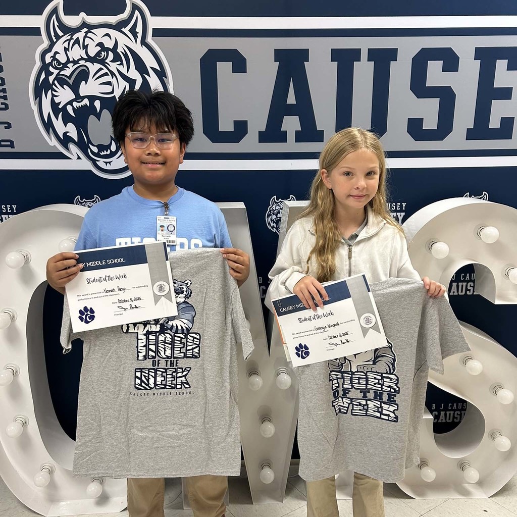 2 students holding up t-shirts and certificates