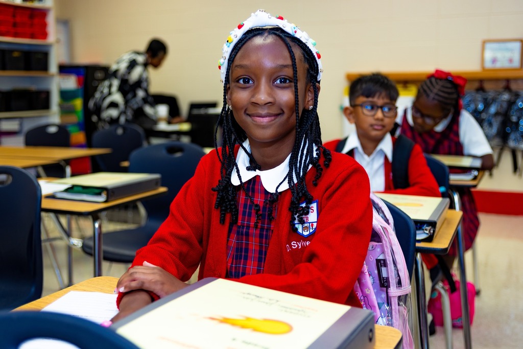 A girl in a red sweater sitting at a desk