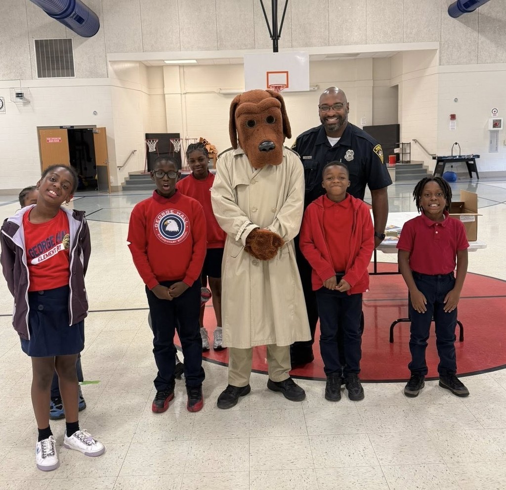 Several elementary students stand with a police officer and McGruff the Crime Dog in a gymnasium