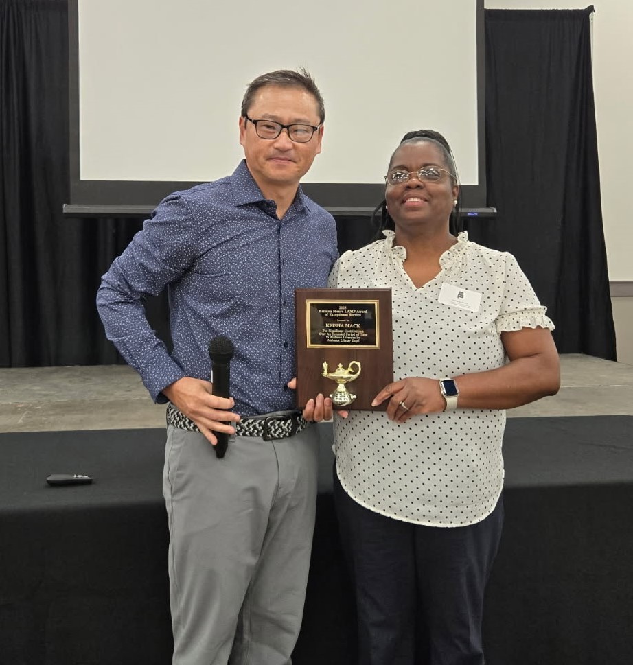 Keisha Mack holding a plaque and standing next to James Taylor