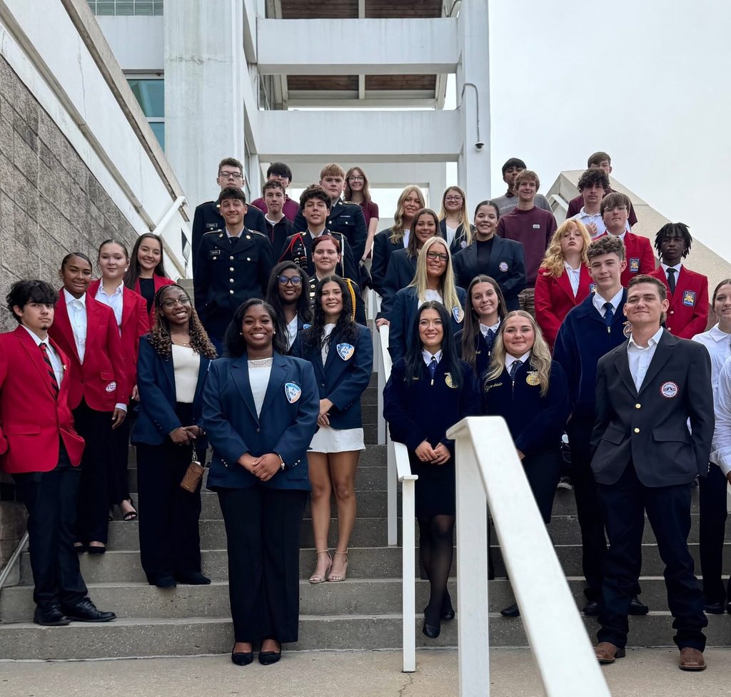 A large group of students in blue and red blazers stands on a staircase