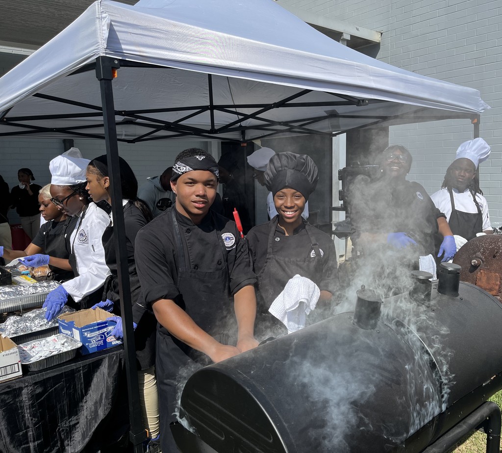 Two culinary students standing behind a grill