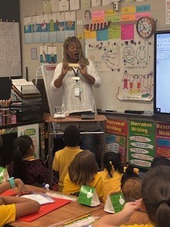 Teacher Michelle Jackson  demonstrates how a change in temperature can cause physical changes in butter as students look on.