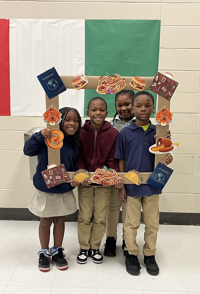 Four students holding a cutout picture frame in front of an Italian flag