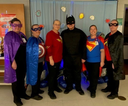 Cafeteria workers dressed as super heroes, with a young man dressed as Batman