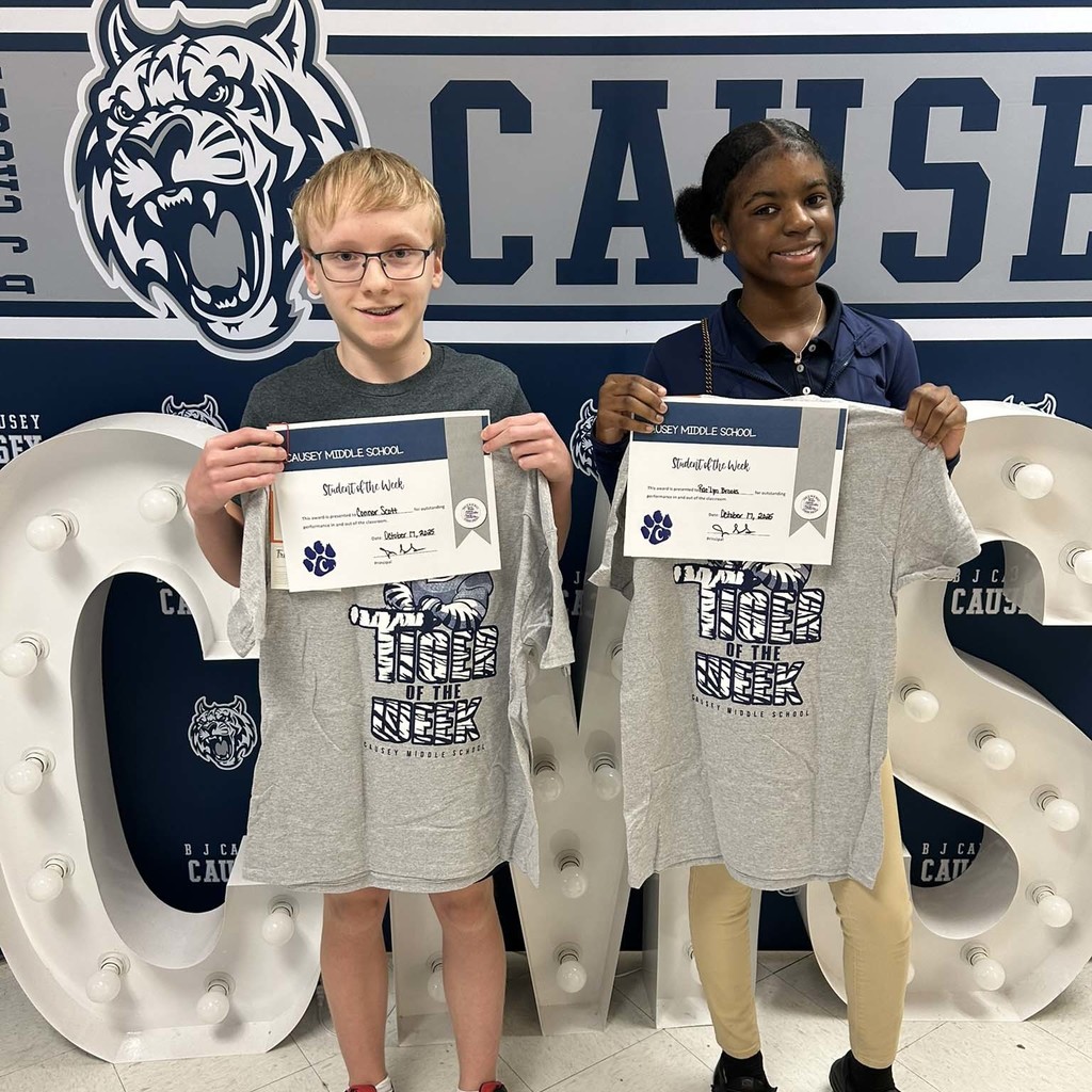2 students holding up t-shirts and certificates