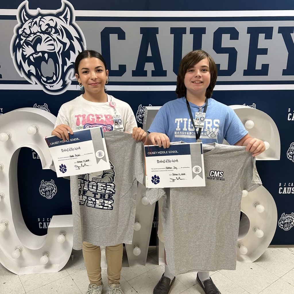 2 students holding up t-shirts and certificates