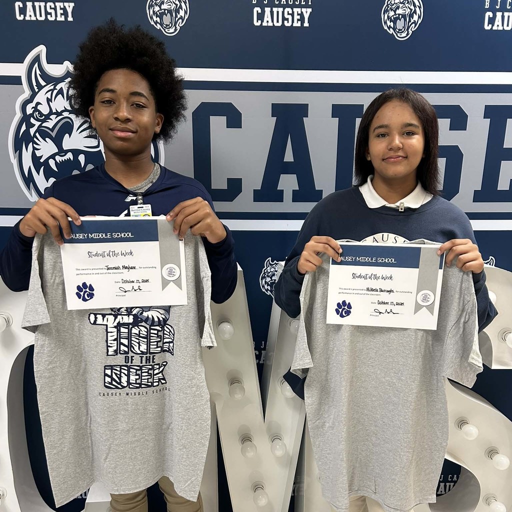 2 students holding up t-shirts and certificates