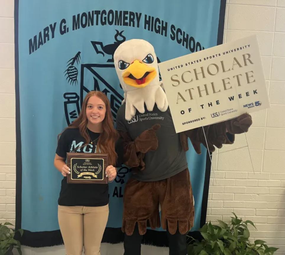 blakely stringer holds a plaque, standing with the U.S. Sports University's eagle mascot