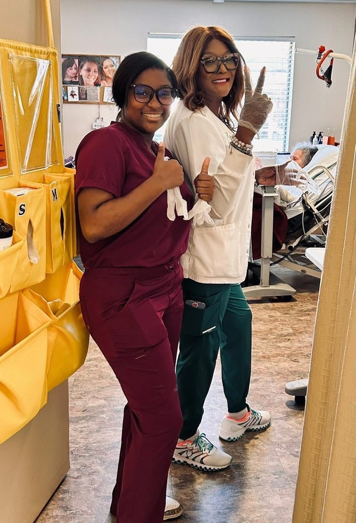 A student and a nurse standing in the doorway of a patient's room
