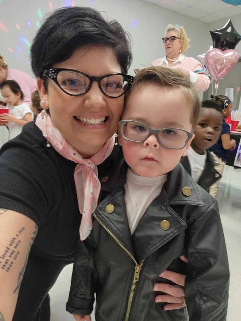 A boy in a leather jacket and a teacher in horn-rimmed glasses and a scarf