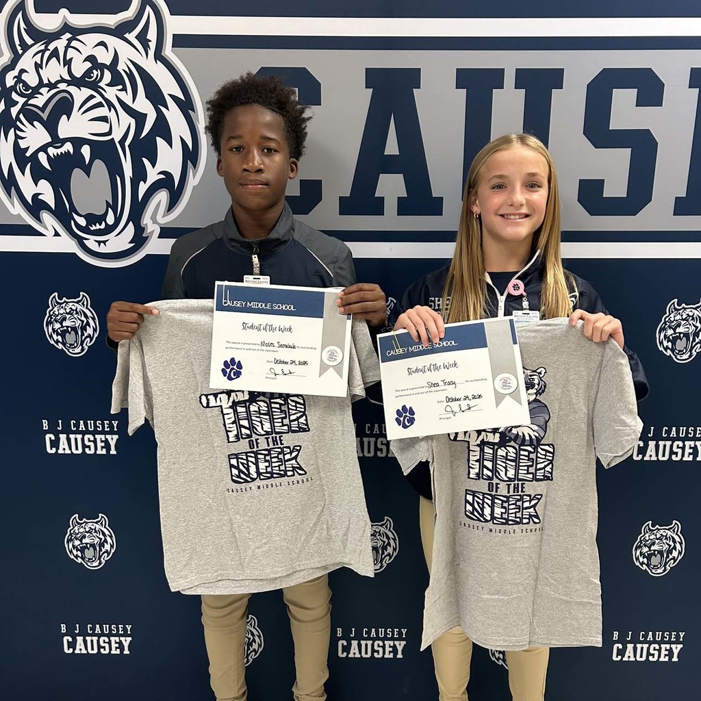 2 students holding up t-shirts and certificates